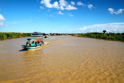 People in boat on river against sky