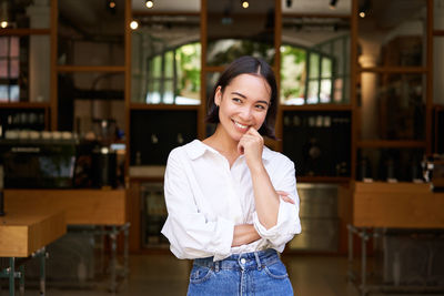 Portrait of young woman standing in cafe