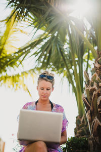 Portrait of woman using mobile phone against trees