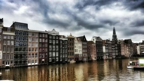 Buildings in city against cloudy sky