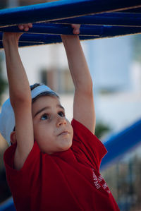 Close-up of cute boy hanging on monkey bars at park