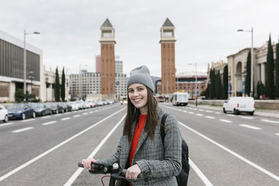 Portrait of smiling young woman standing in city