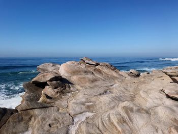 Rock formations on shore against clear sky