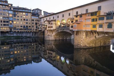 Ponte vecchio reflected in the arno river at sunset