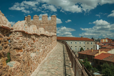 Pathway over old thick wall with battlement and large tower made of stone in avila, spain.