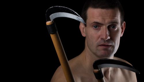 Close-up portrait of mature man holding work tool over black background