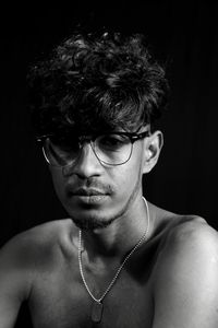 Portrait of young man wearing eyeglasses against black background