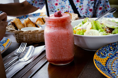 Strawberry shake, vegetable salad and bread on the table.