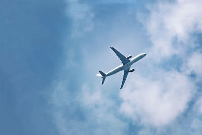 Passenger plane flies in sky, gaining height, bottom view. empty place for copy space.