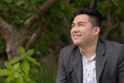 Smiling man looking away against plant