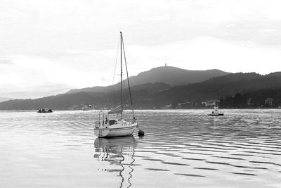 Sailboats moored in sea against sky