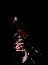 Portrait of woman standing against black background