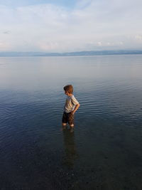 Rear view of boy in sea against sky