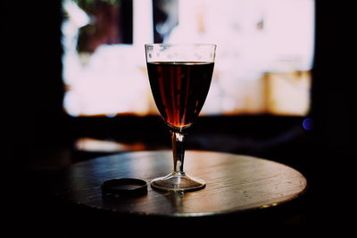 Close-up of drink on table against window in darkroom