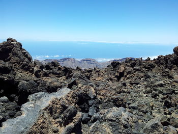 Scenic view of sea and mountains against clear blue sky