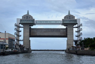 View of building by river against cloudy sky