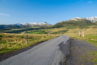 Road amidst landscape against blue sky