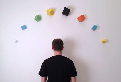 Rear view of man standing by wall with colorful blocks
