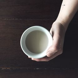 Close-up of hand holding coffee cup on table