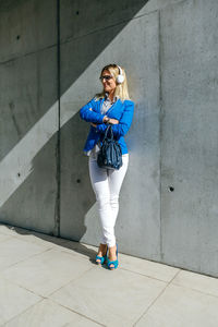 Portrait of young woman standing against wall