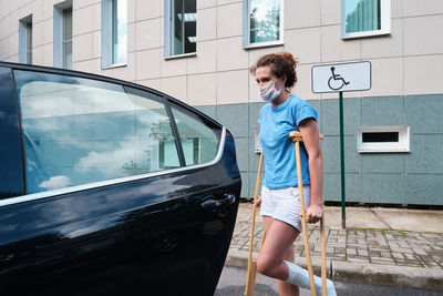 A woman with an injured leg gets into a car. orthopedic plaster, orthopedic crutches. 