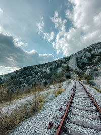 View of railroad tracks by snowcapped mountain against sky