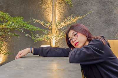 Portrait of woman sitting by plant