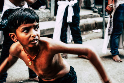 Portrait of shirtless boy looking at street in city