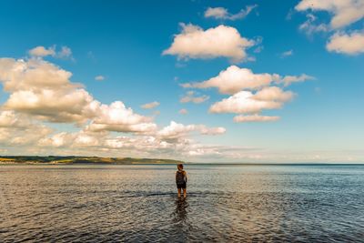 Woman standing on beach against sky