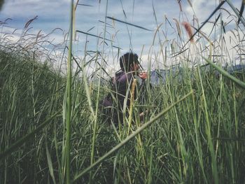 Man standing by plants on field against sky