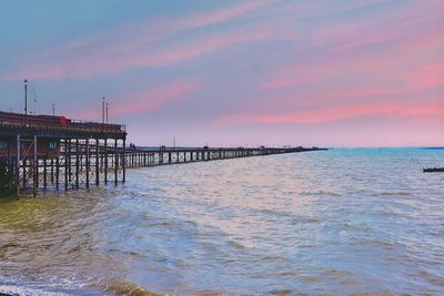 Pier over sea against sky during sunset