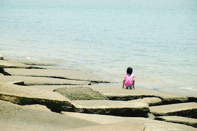 Rear view of woman standing on beach against clear sky