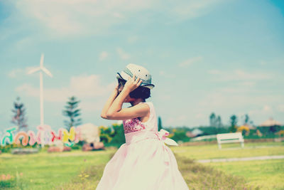 Girl wearing hat at park against sky