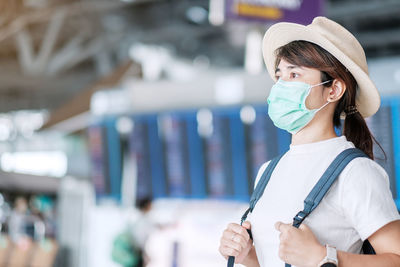 Woman with mask looking away in airport outdoors