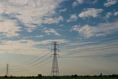 Low angle view of electricity pylon against sky during sunset