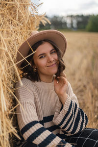 Portrait of smiling young woman wearing hat on field