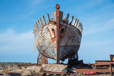 Low angle view of old rusty wheel against sky