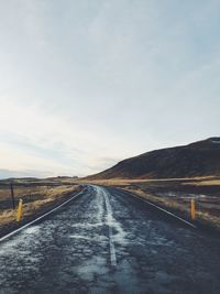 Empty road along landscape against sky