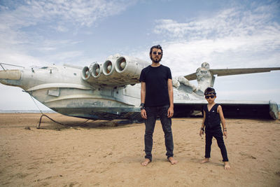 Family a boy and his father in rocker clothes stand ekranoplan plane by the sea in dagestan