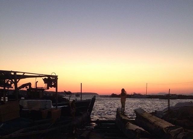 SILHOUETTE MAN ON BOAT AGAINST CLEAR SKY AT SUNSET