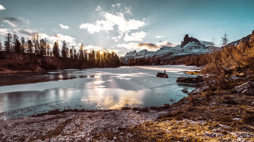 Scenic view of lake by snowcapped mountains against sky