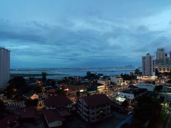 High angle view of city lit up against cloudy sky