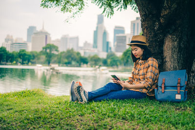 Young woman using mobile phone while sitting by plants