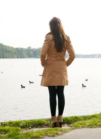 Rear view of woman standing at lakeshore