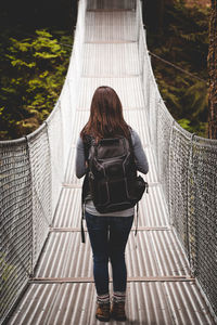 Rear view of woman walking on footbridge