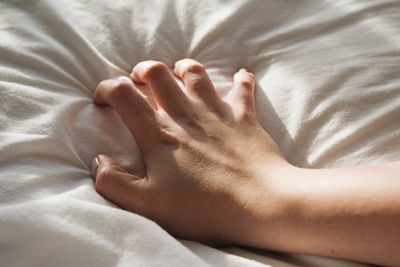 Cropped hand of woman on bed at home