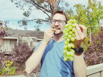 Portrait of smiling man eating grapes 
