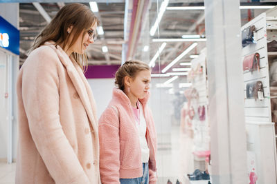 Mother and daughter look at the shop window of the shopping day