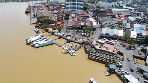 High angle view of boats moored at harbor by buildings in city