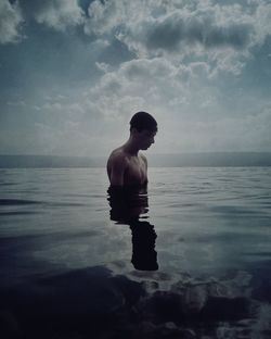 Full length of shirtless man in swimming pool against sea